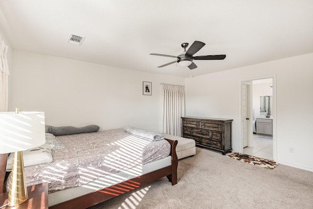 carpeted bedroom with ensuite bath and ceiling fan