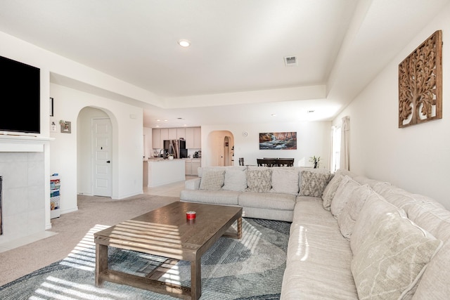 living room with light carpet and a tile fireplace