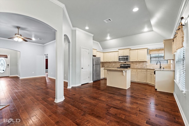 kitchen with light stone countertops, a center island, sink, stainless steel appliances, and ornamental molding