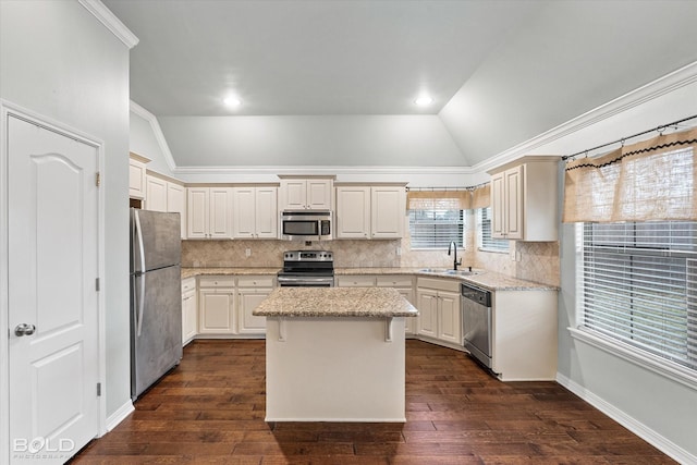 kitchen with lofted ceiling, sink, light stone countertops, a kitchen island, and stainless steel appliances