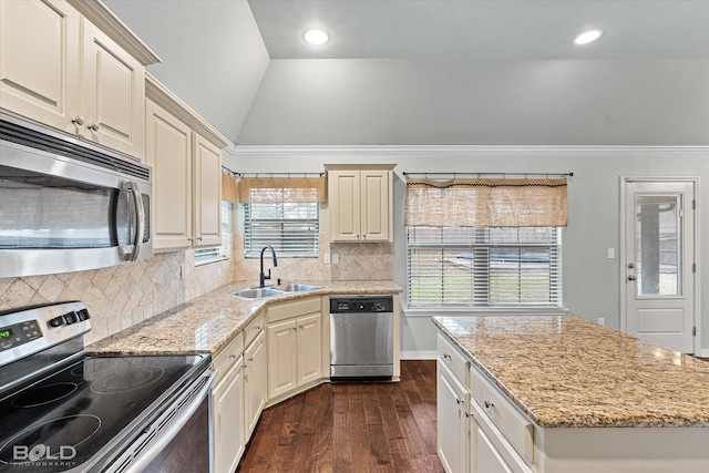 kitchen featuring light stone countertops, appliances with stainless steel finishes, a wealth of natural light, sink, and lofted ceiling