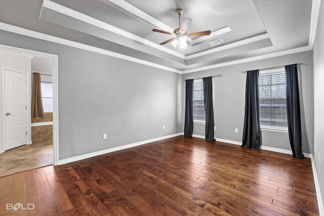 spare room with a tray ceiling, ceiling fan, dark wood-type flooring, and ornamental molding