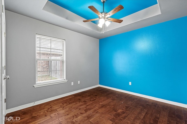 spare room with hardwood / wood-style floors, ceiling fan, and a tray ceiling