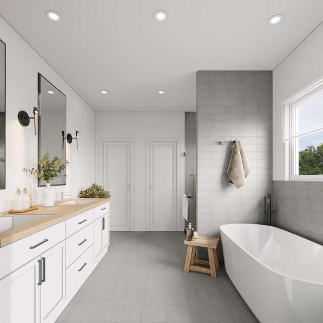 bathroom featuring a bath, vanity, and tile walls