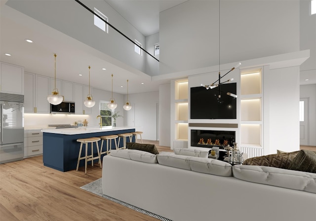 living room featuring built in shelves, light wood-type flooring, and a towering ceiling