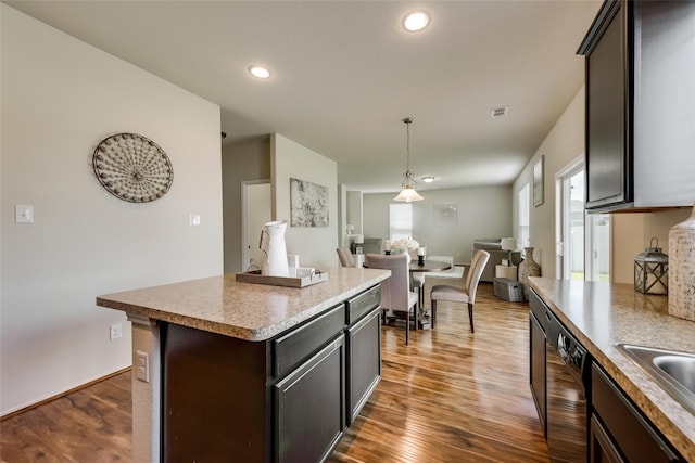 kitchen with dishwashing machine, dark brown cabinets, a kitchen island, and dark hardwood / wood-style floors