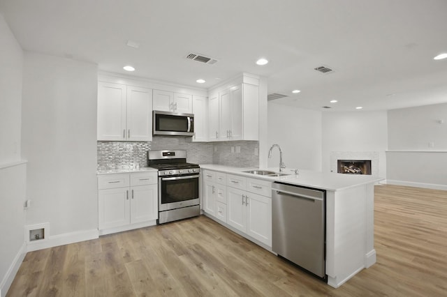 kitchen featuring kitchen peninsula, stainless steel appliances, white cabinets, and sink