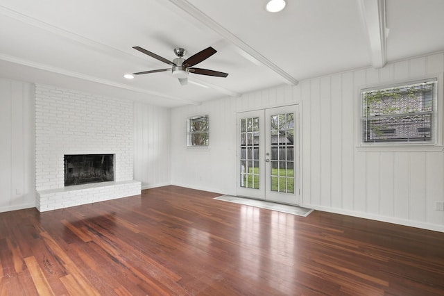 unfurnished living room featuring dark wood-type flooring, french doors, beam ceiling, a fireplace, and ceiling fan