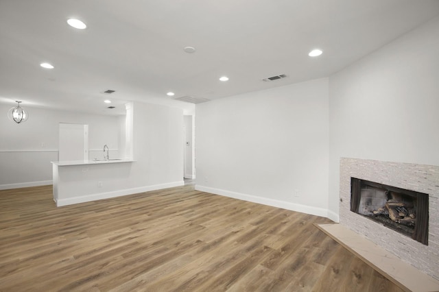 unfurnished living room with sink, an inviting chandelier, and hardwood / wood-style floors