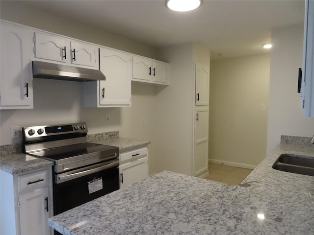 kitchen with electric stove, sink, light stone countertops, light tile patterned flooring, and white cabinetry