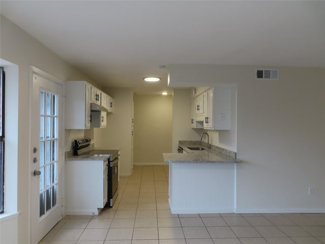 kitchen featuring sink, light tile patterned floors, white cabinetry, white range oven, and kitchen peninsula