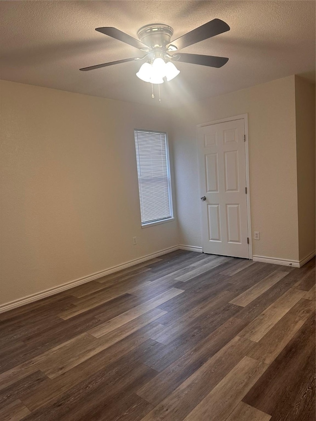 spare room with a textured ceiling, ceiling fan, and dark wood-type flooring