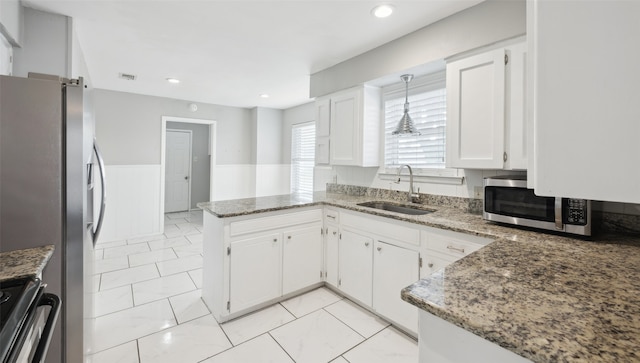 kitchen featuring appliances with stainless steel finishes, pendant lighting, white cabinetry, sink, and kitchen peninsula