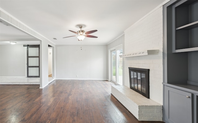 unfurnished living room featuring dark hardwood / wood-style flooring, a brick fireplace, ornamental molding, and ceiling fan