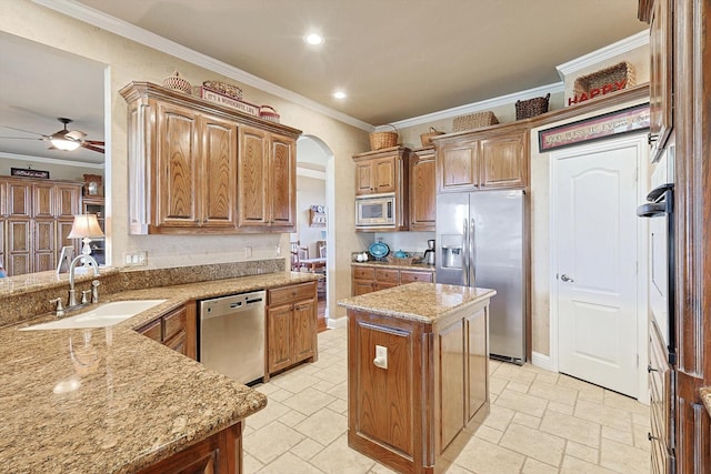 kitchen featuring a center island, sink, ceiling fan, light stone countertops, and appliances with stainless steel finishes