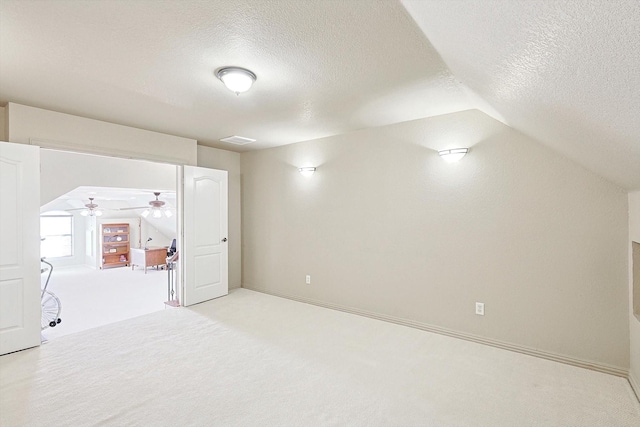 bonus room with vaulted ceiling, light carpet, ceiling fan, and a textured ceiling