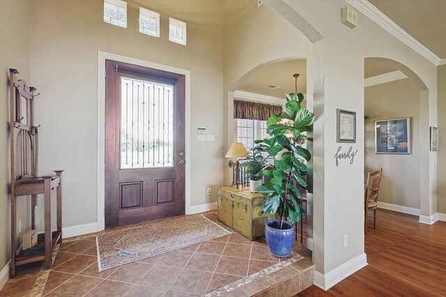 foyer entrance with a healthy amount of sunlight, ornamental molding, and dark tile patterned floors