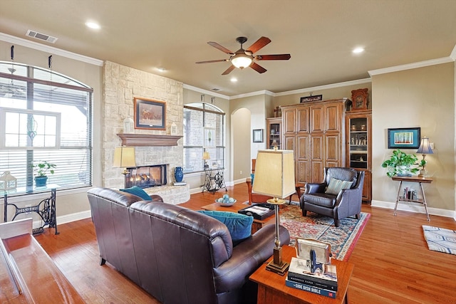 living room featuring crown molding, a fireplace, ceiling fan, and hardwood / wood-style flooring