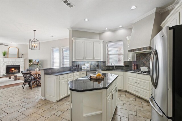 kitchen with a center island, tasteful backsplash, ventilation hood, a fireplace, and appliances with stainless steel finishes