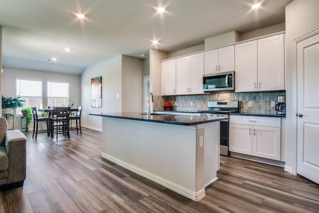 kitchen with appliances with stainless steel finishes, a kitchen island with sink, dark wood-type flooring, sink, and white cabinets