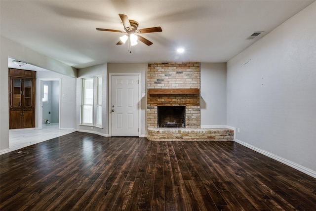 unfurnished living room with a brick fireplace, dark hardwood / wood-style flooring, and ceiling fan