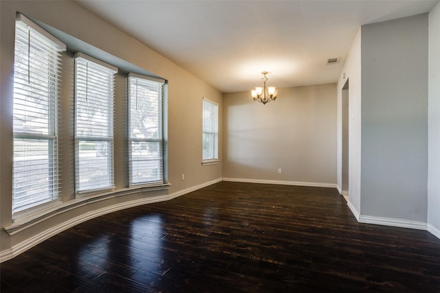 spare room with dark wood-type flooring and a chandelier