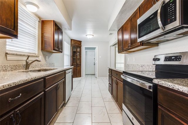 kitchen featuring a healthy amount of sunlight, appliances with stainless steel finishes, sink, and light stone counters