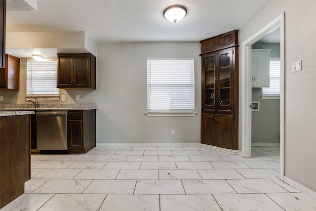 kitchen with stainless steel dishwasher, dark brown cabinetry, and light stone countertops