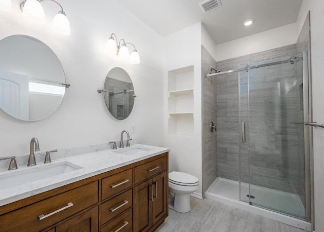 bathroom featuring vanity, a shower with shower door, and toilet