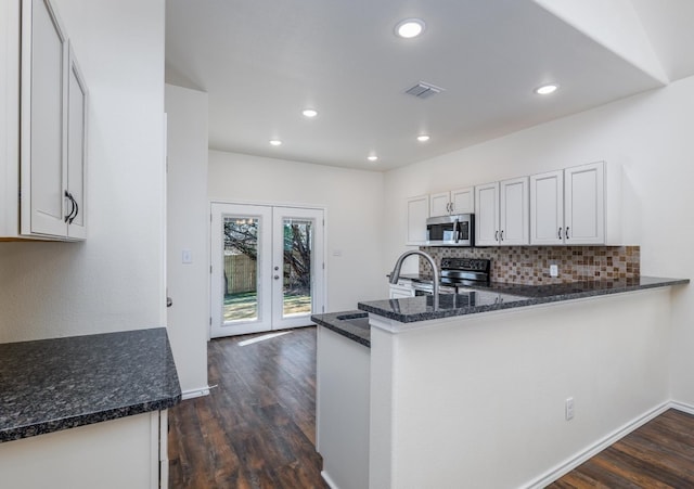 kitchen featuring french doors, kitchen peninsula, appliances with stainless steel finishes, dark hardwood / wood-style flooring, and white cabinetry