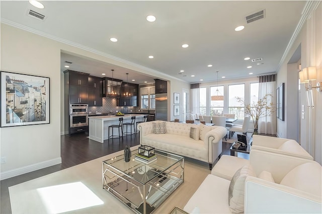 living room featuring sink, ornamental molding, and dark wood-type flooring