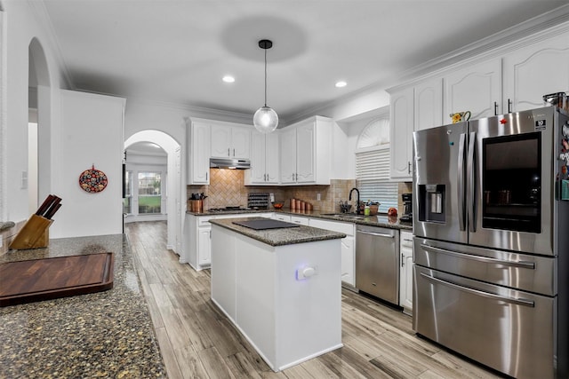 kitchen featuring appliances with stainless steel finishes, a sink, arched walkways, white cabinetry, and under cabinet range hood