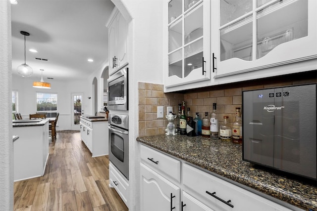 kitchen featuring appliances with stainless steel finishes, tasteful backsplash, pendant lighting, light hardwood / wood-style floors, and white cabinetry