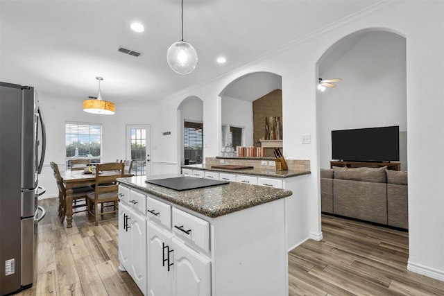 kitchen featuring visible vents, a center island, arched walkways, light wood-type flooring, and freestanding refrigerator