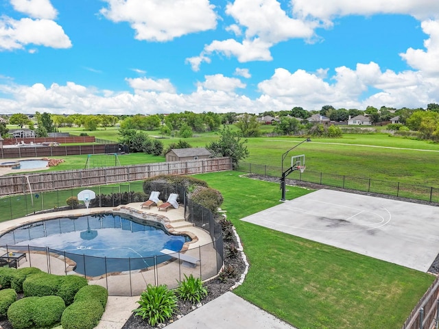 view of swimming pool featuring a lawn, fence, basketball hoop, and a fenced in pool