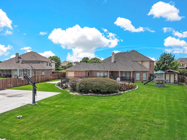 back of property with brick siding, fence, a yard, and a storage unit