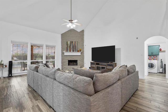 living area featuring washer / dryer, ceiling fan, wood finished floors, and high vaulted ceiling