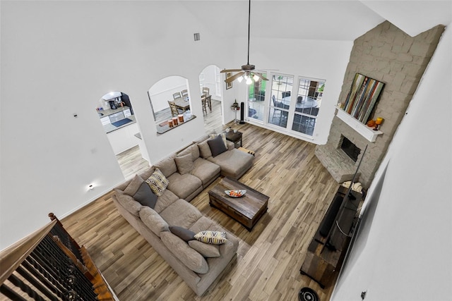 living room with hardwood / wood-style floors, ceiling fan, a fireplace, and high vaulted ceiling