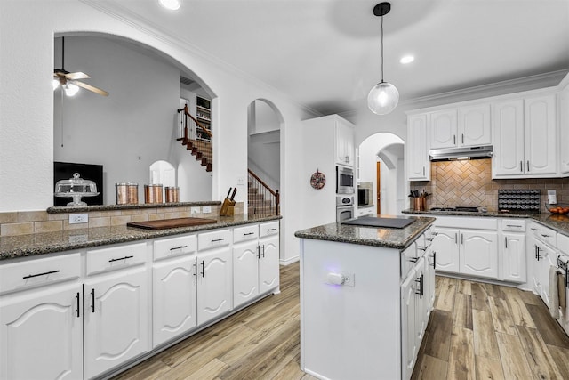 kitchen with tasteful backsplash, dark stone countertops, white cabinetry, and hanging light fixtures