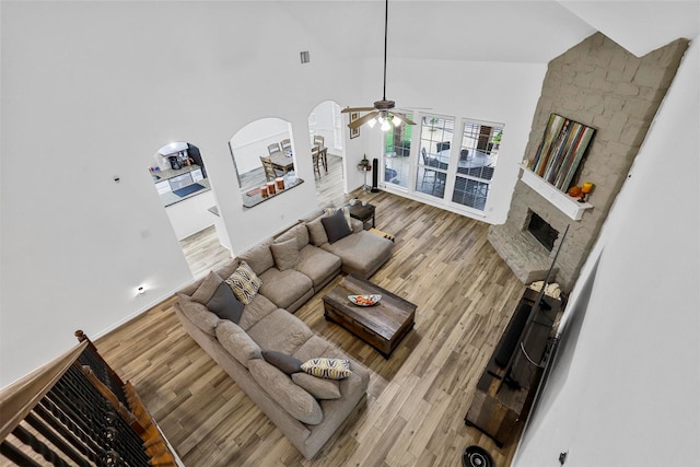living room featuring a ceiling fan, arched walkways, wood finished floors, and high vaulted ceiling