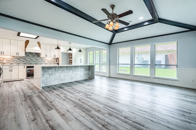 kitchen featuring white cabinetry, hanging light fixtures, wine cooler, lofted ceiling, and custom range hood