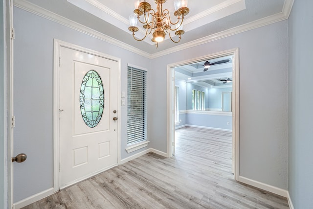 entryway featuring ceiling fan with notable chandelier, a tray ceiling, light hardwood / wood-style flooring, and ornamental molding