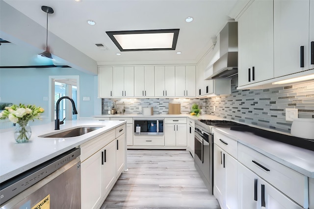 kitchen featuring white cabinets, premium range hood, stainless steel dishwasher, and sink