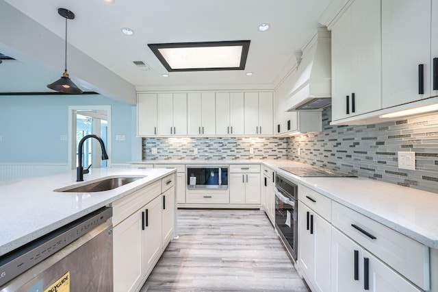 kitchen with white cabinets, custom exhaust hood, sink, and appliances with stainless steel finishes