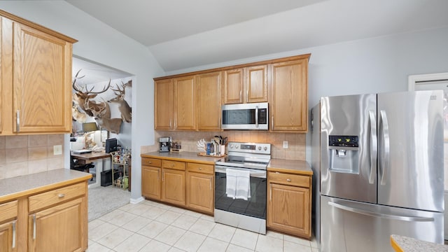 kitchen with tasteful backsplash, light tile patterned floors, stainless steel appliances, and vaulted ceiling