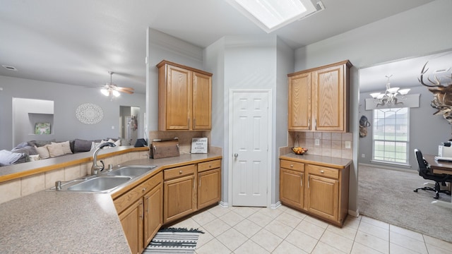 kitchen featuring light carpet, backsplash, ceiling fan with notable chandelier, and sink