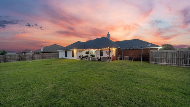 back house at dusk with central AC and a lawn