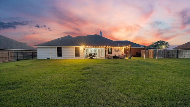 back house at dusk with an outdoor living space, a patio area, and a yard