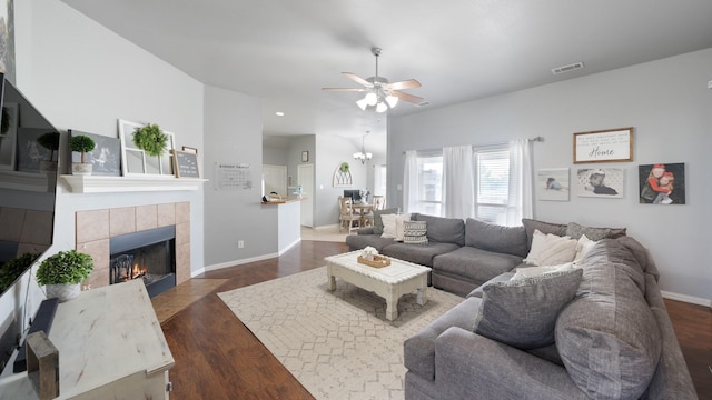 living room with a fireplace, ceiling fan with notable chandelier, and dark hardwood / wood-style floors