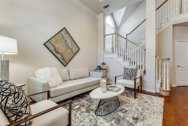 living room featuring a towering ceiling, ornamental molding, and dark hardwood / wood-style floors